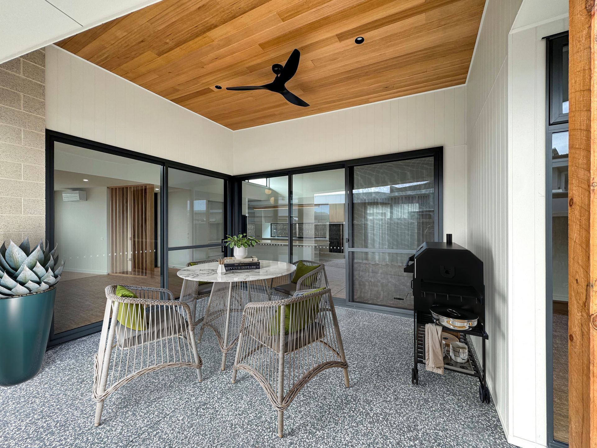 A patio with a table and chairs and a ceiling fan.