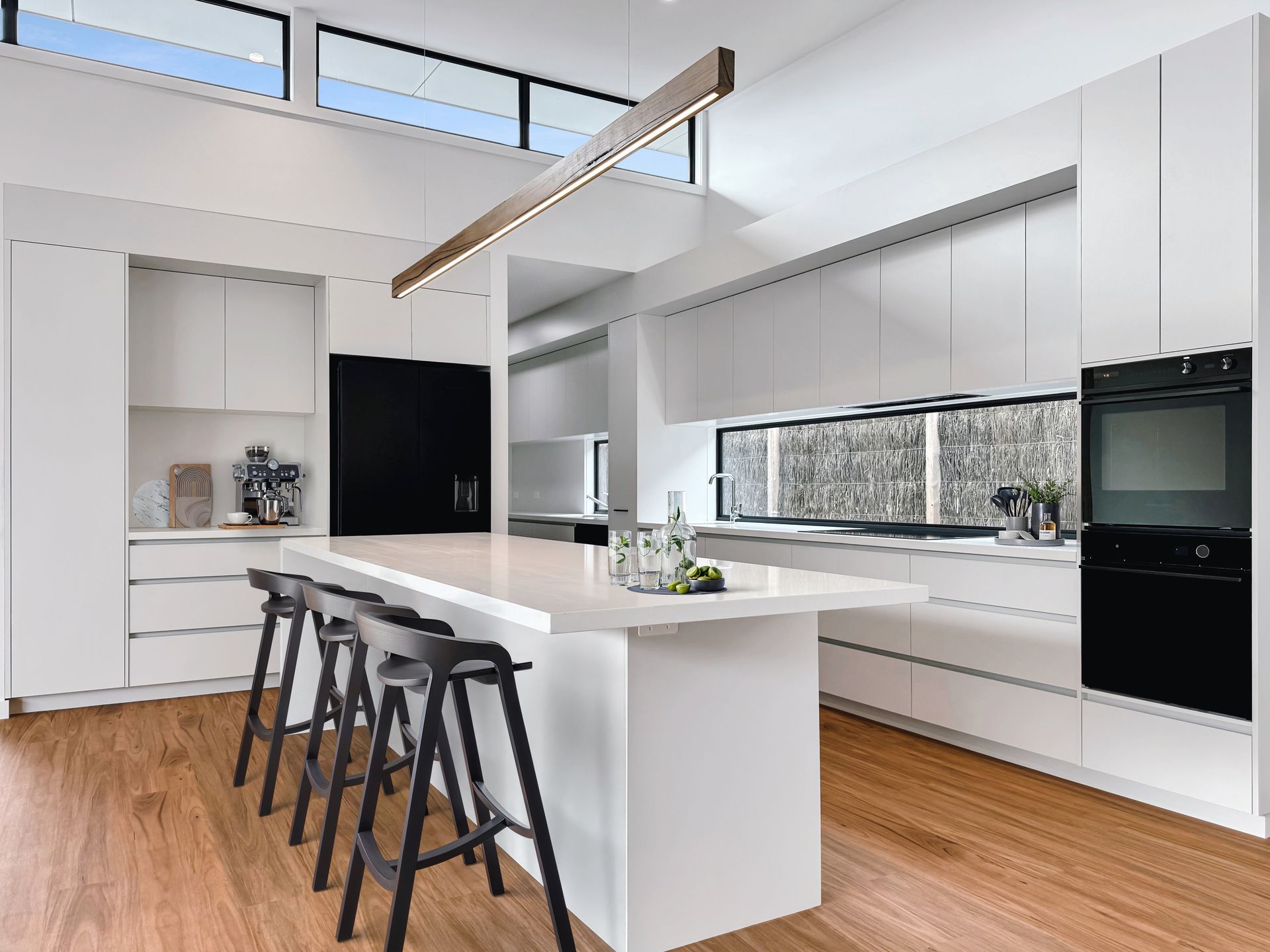 A kitchen with white cabinets and a large island with stools.