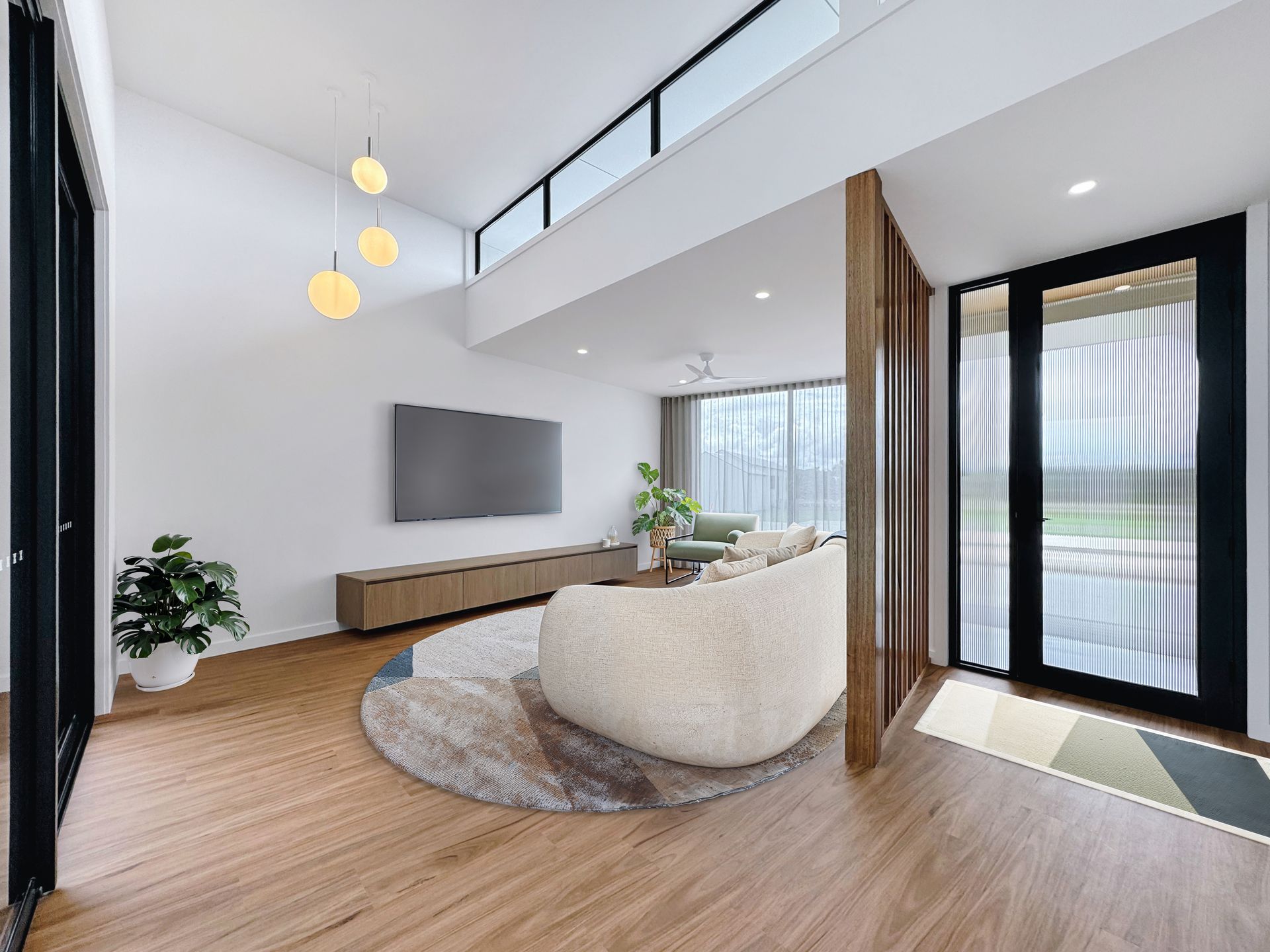 A living room with a couch , chair , television and sliding glass doors.