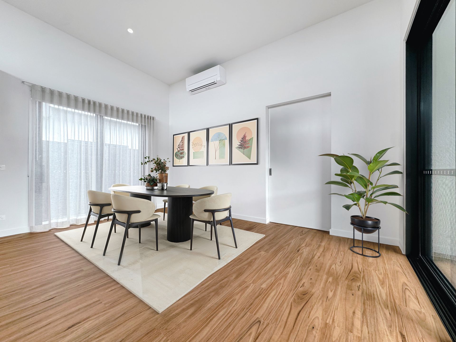 A dining room with a table and chairs and a plant.