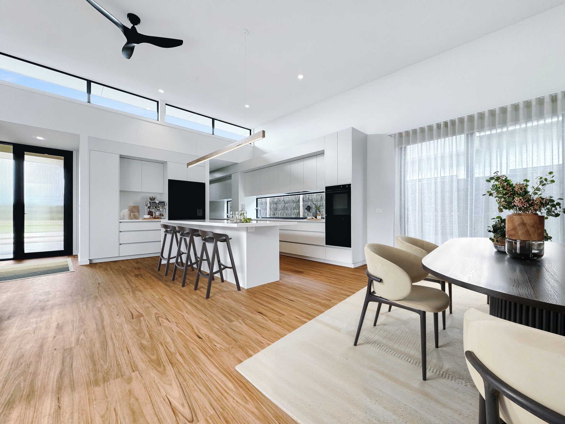 A kitchen and dining room in a house with hardwood floors and a ceiling fan.
