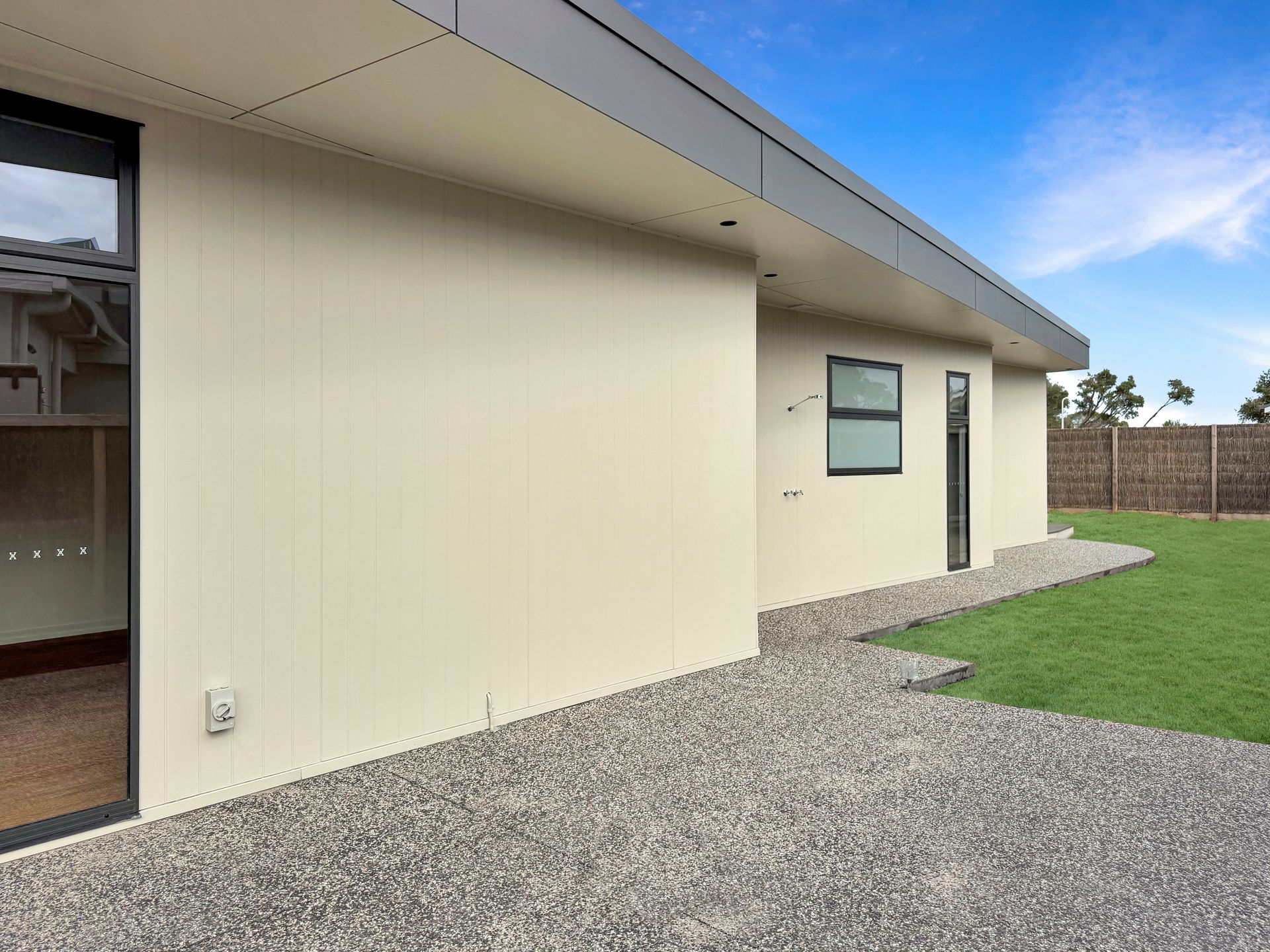 A white house with a gravel driveway in front of it.