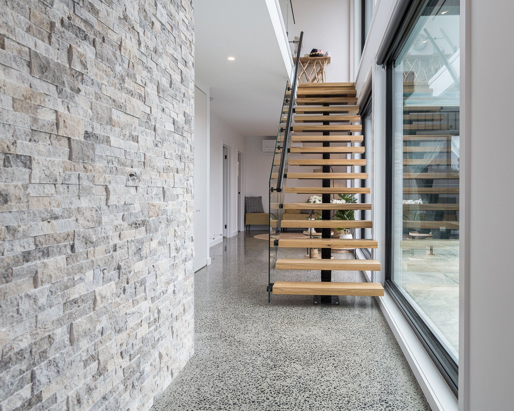 A hallway with a wooden staircase and a brick wall.