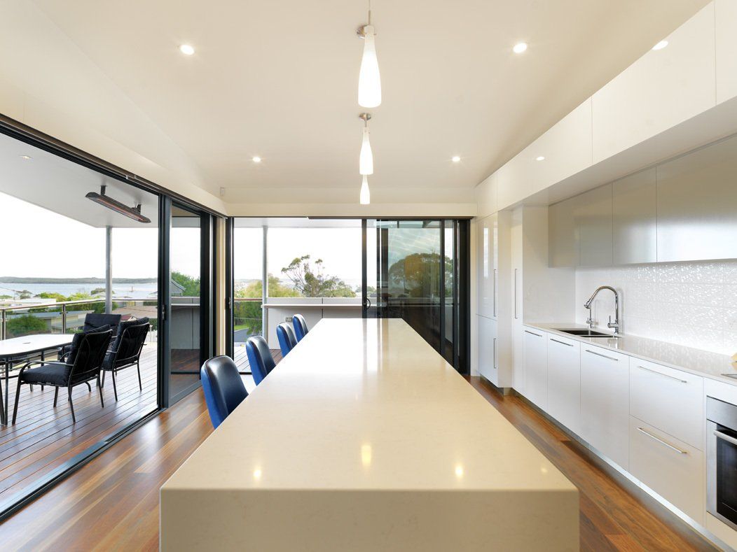 A kitchen with a long table and sliding glass doors
