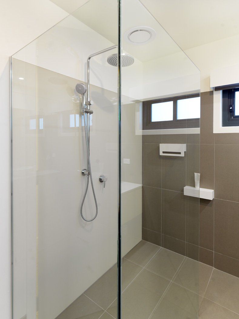 A bathroom with a walk in shower and a window.