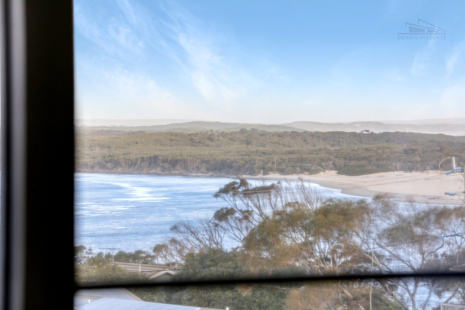 A window with a view of a beach and a body of water.