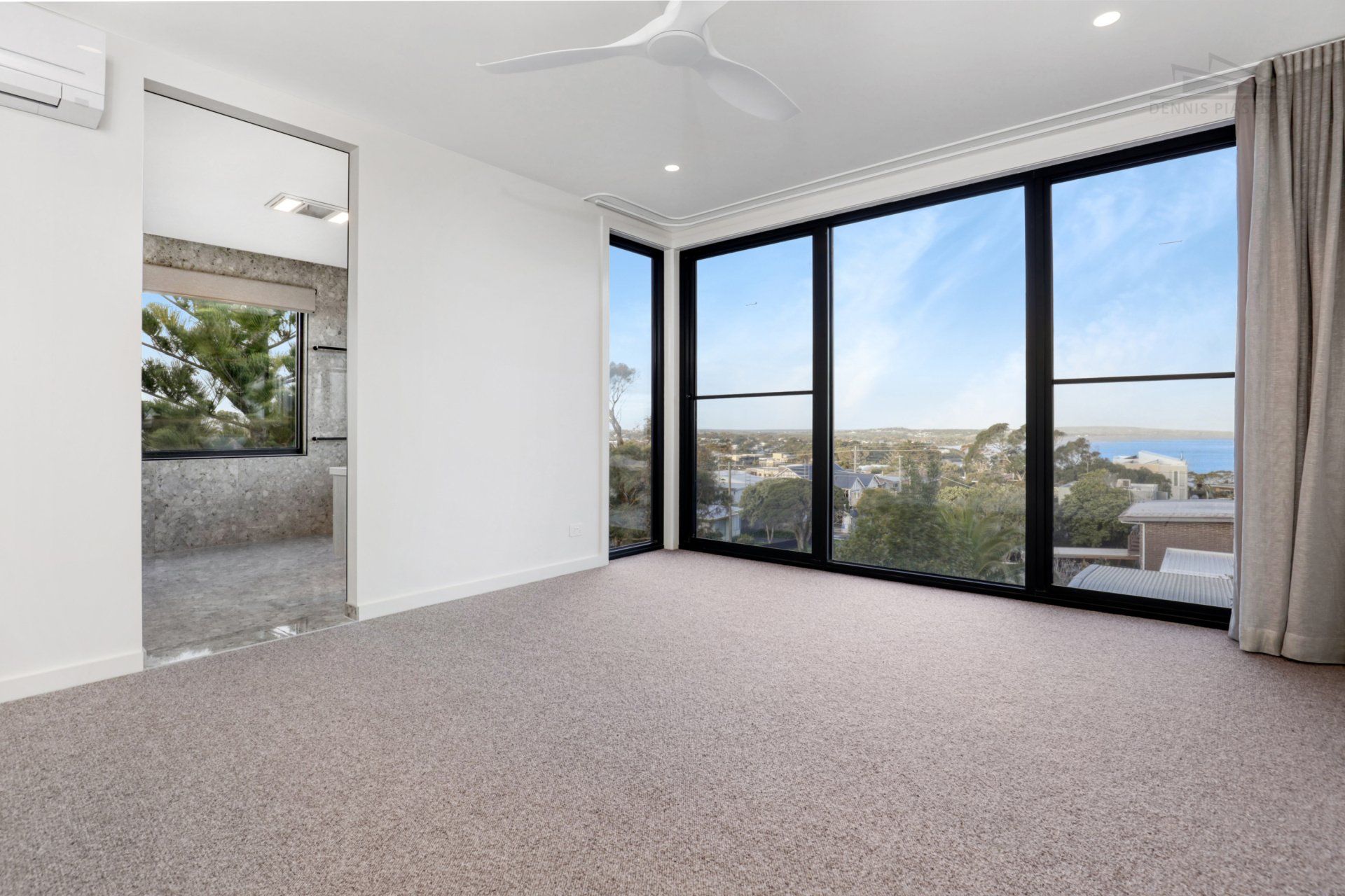 An empty room with a lot of windows and a ceiling fan.