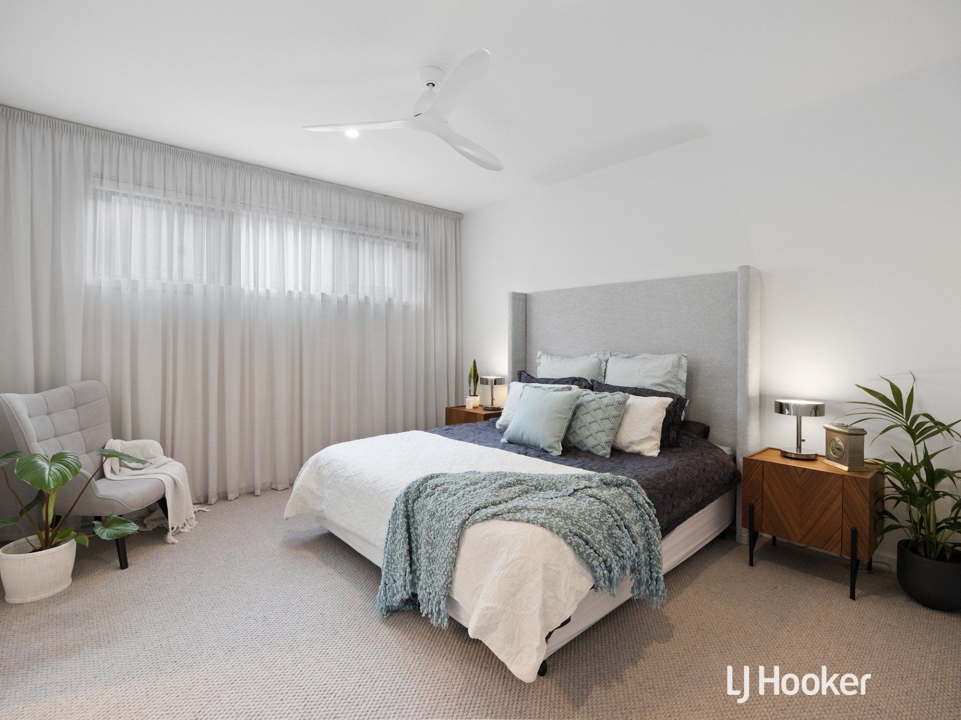 A bedroom with a bed , chair , nightstand and ceiling fan.