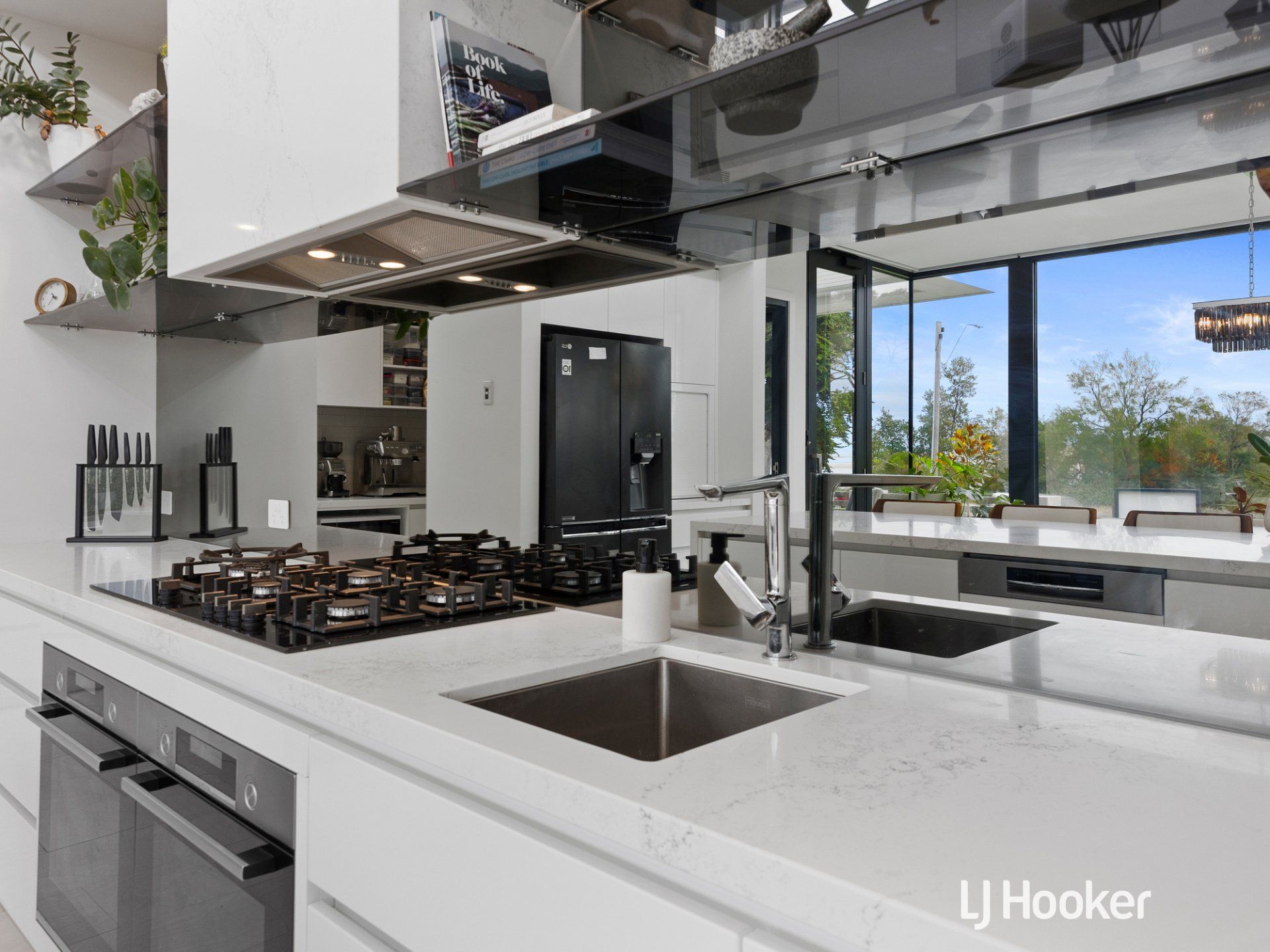 A kitchen with a sink , stove , oven , and refrigerator.