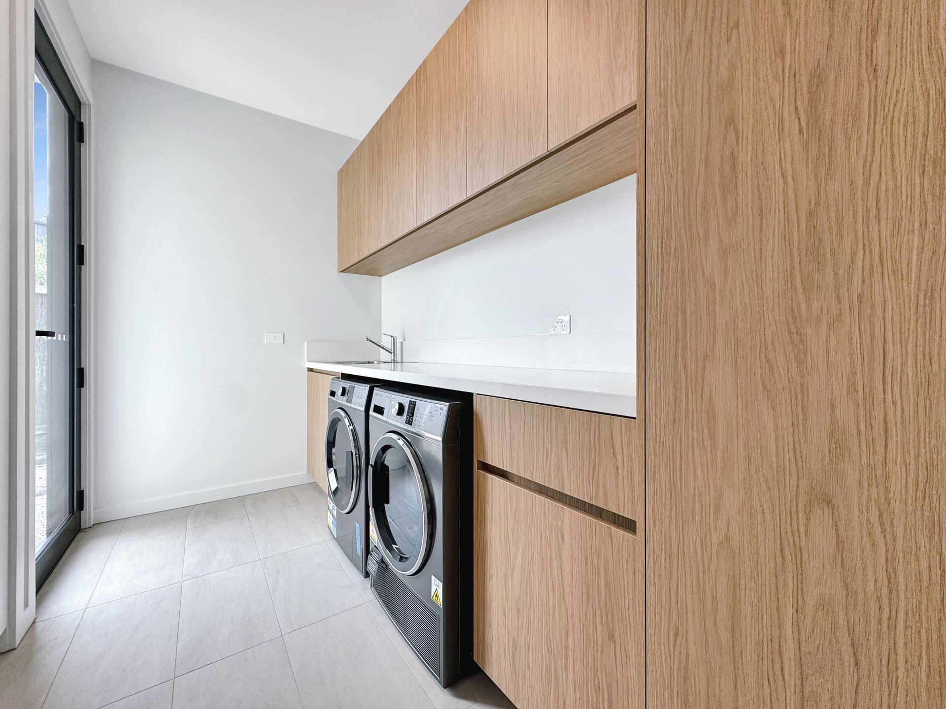 A laundry room with a washer and dryer and wooden cabinets.