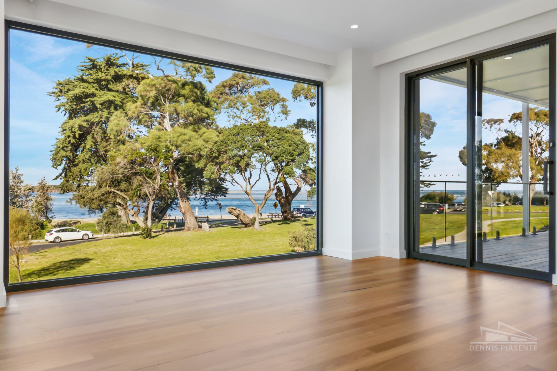 An empty room with a large window and a view of the ocean.