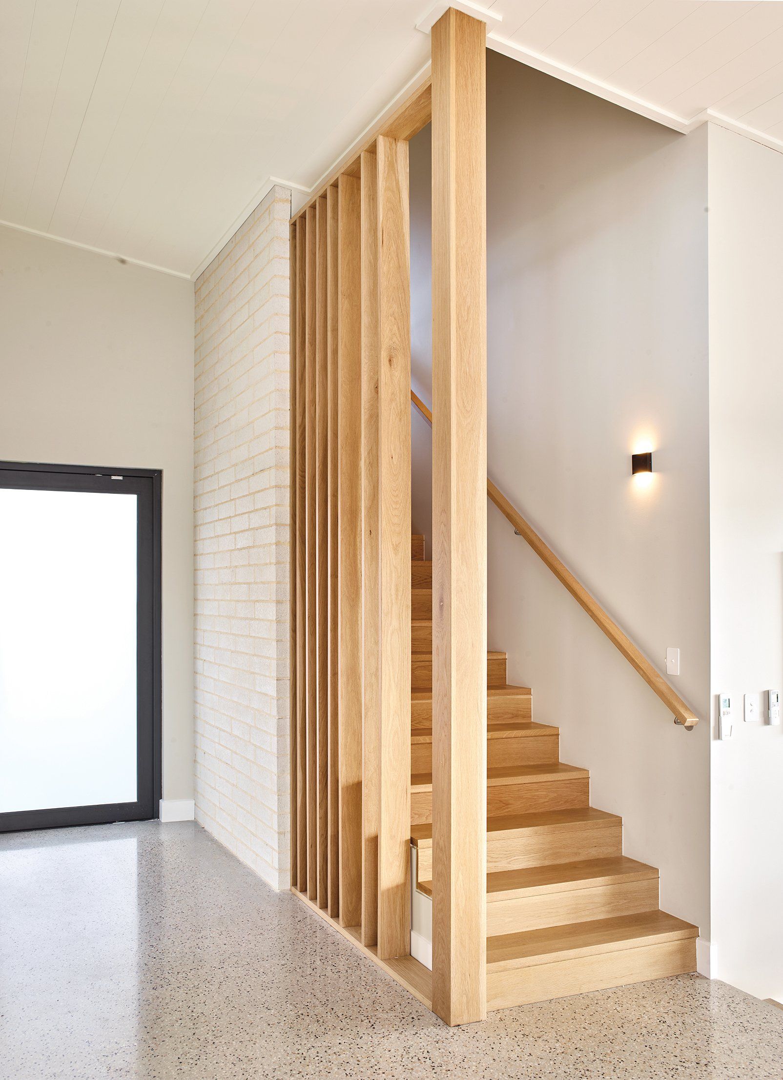 A wooden staircase with a wooden railing in a hallway.