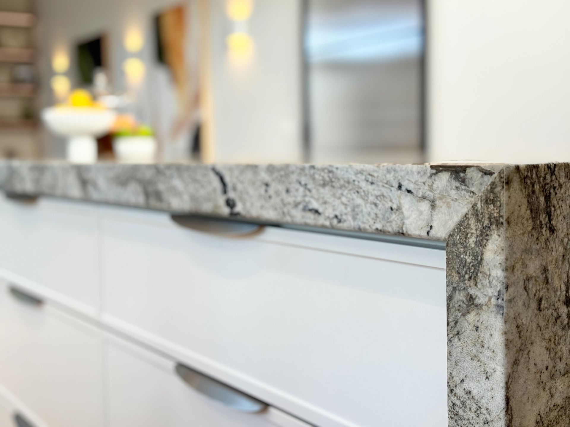 Close-up of a white kitchen cabinet with a gray granite countertop.