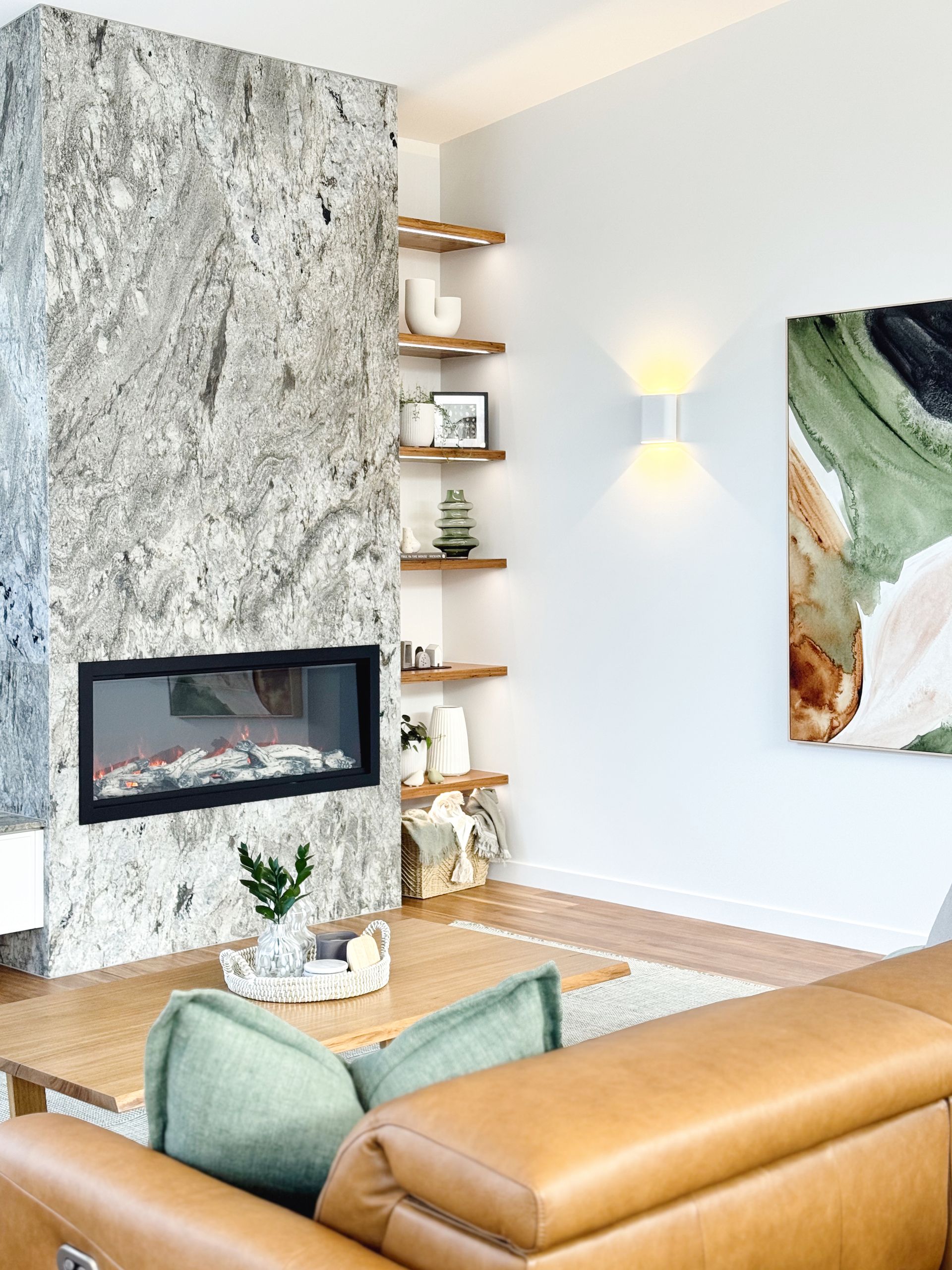 Living room with stone fireplace, wooden shelves, and abstract art.