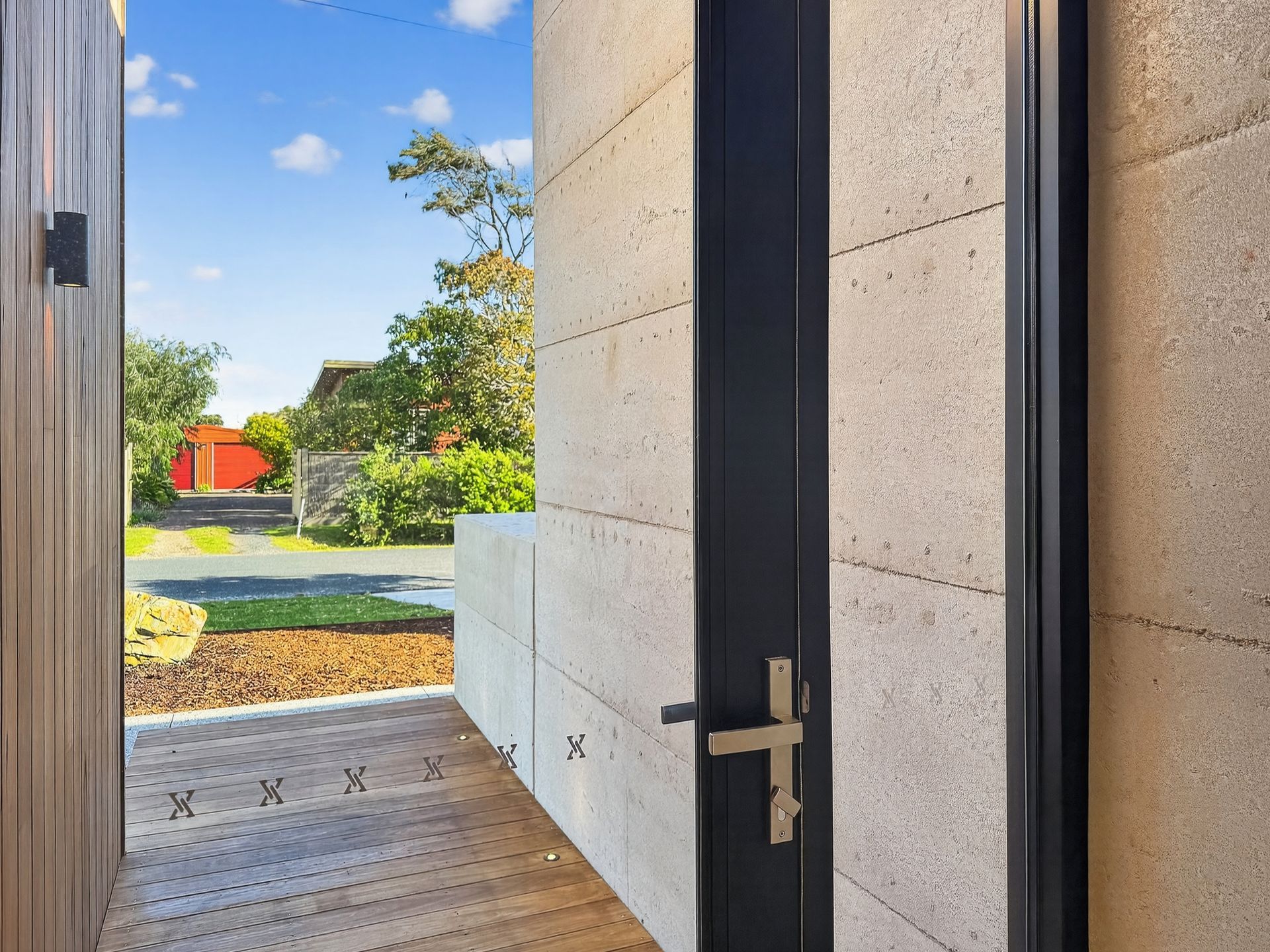 Open doorway with a view of a street; beige textured walls, dark door with gold handle.