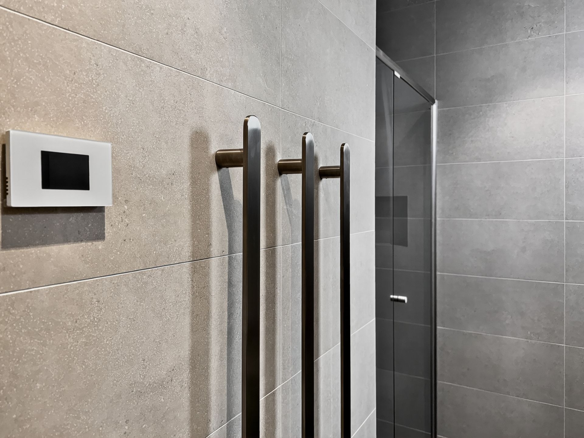 Modern bathroom with tiled walls, towel warmer, and glass shower enclosure.