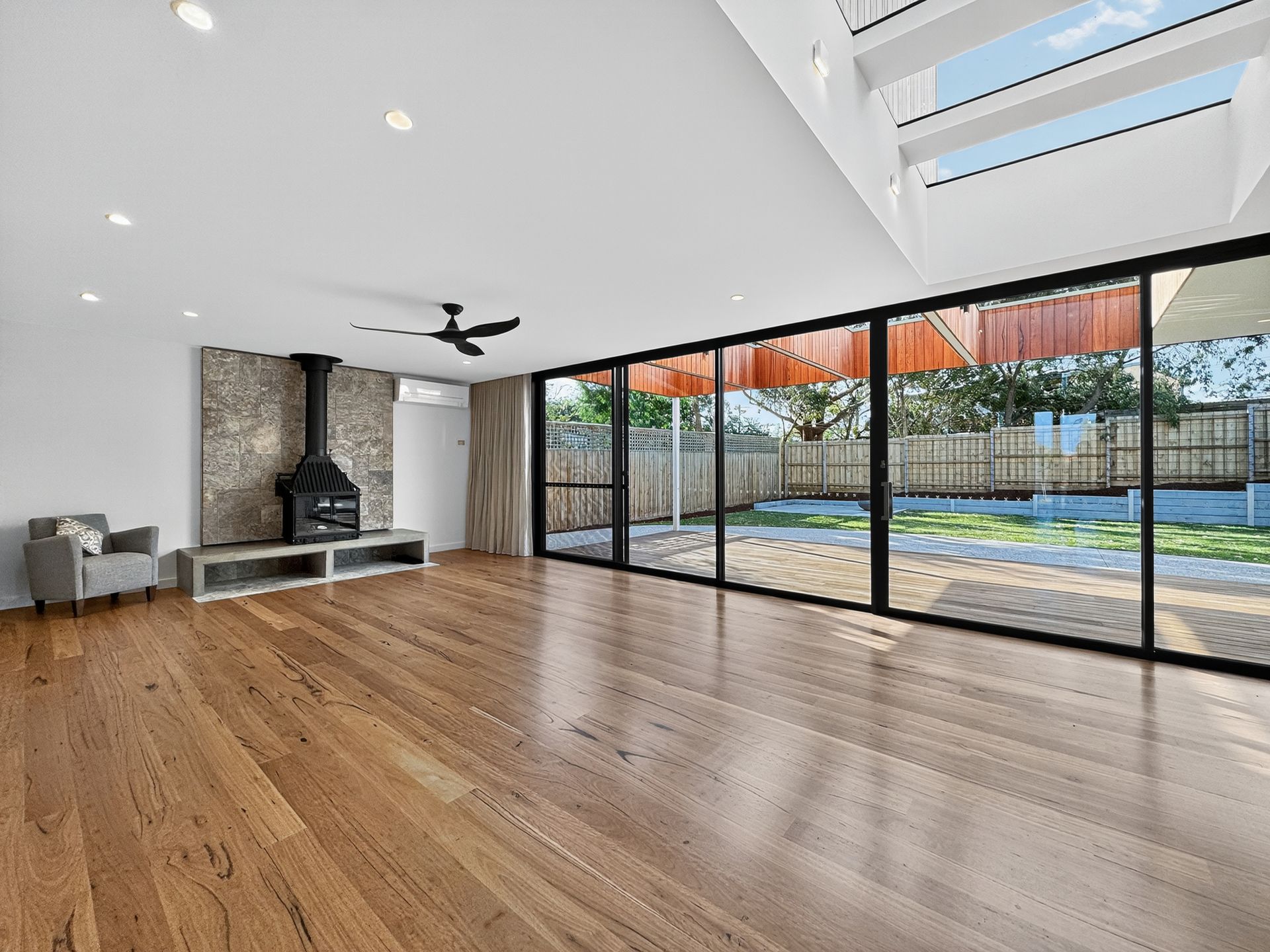Empty living room with wood flooring, fireplace, and large sliding glass doors leading to a backyard.