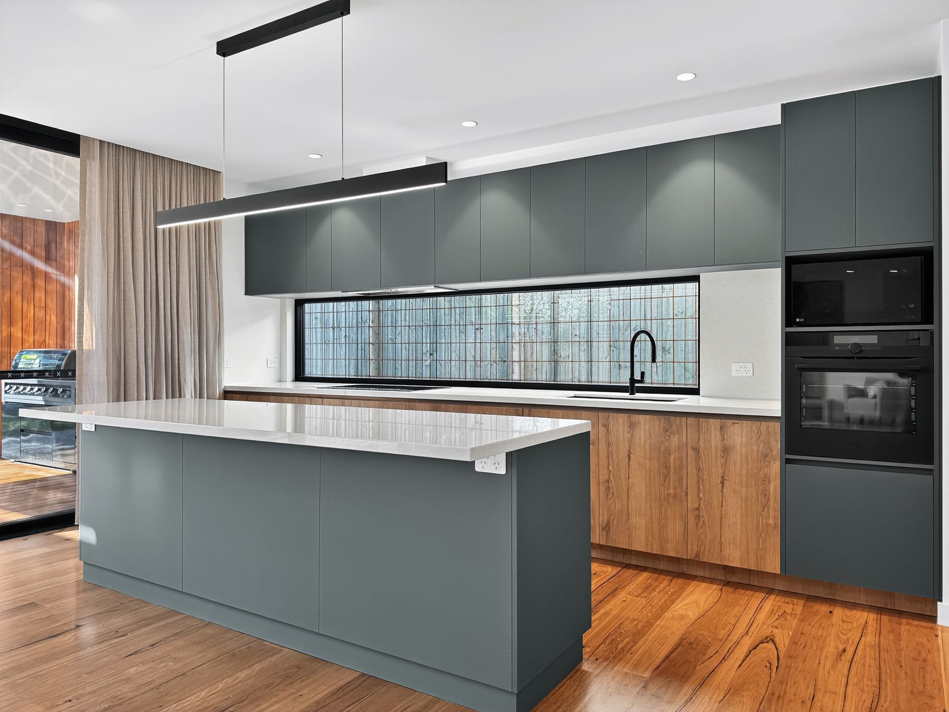 Modern kitchen with gray and wood cabinets, island, and long window.