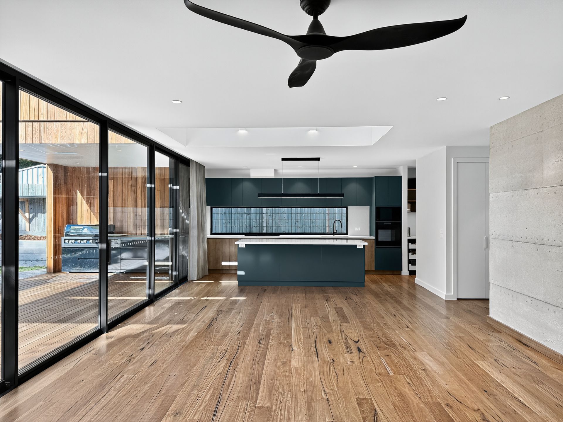 Spacious modern kitchen with dark blue cabinets, island, and large windows leading to a patio.