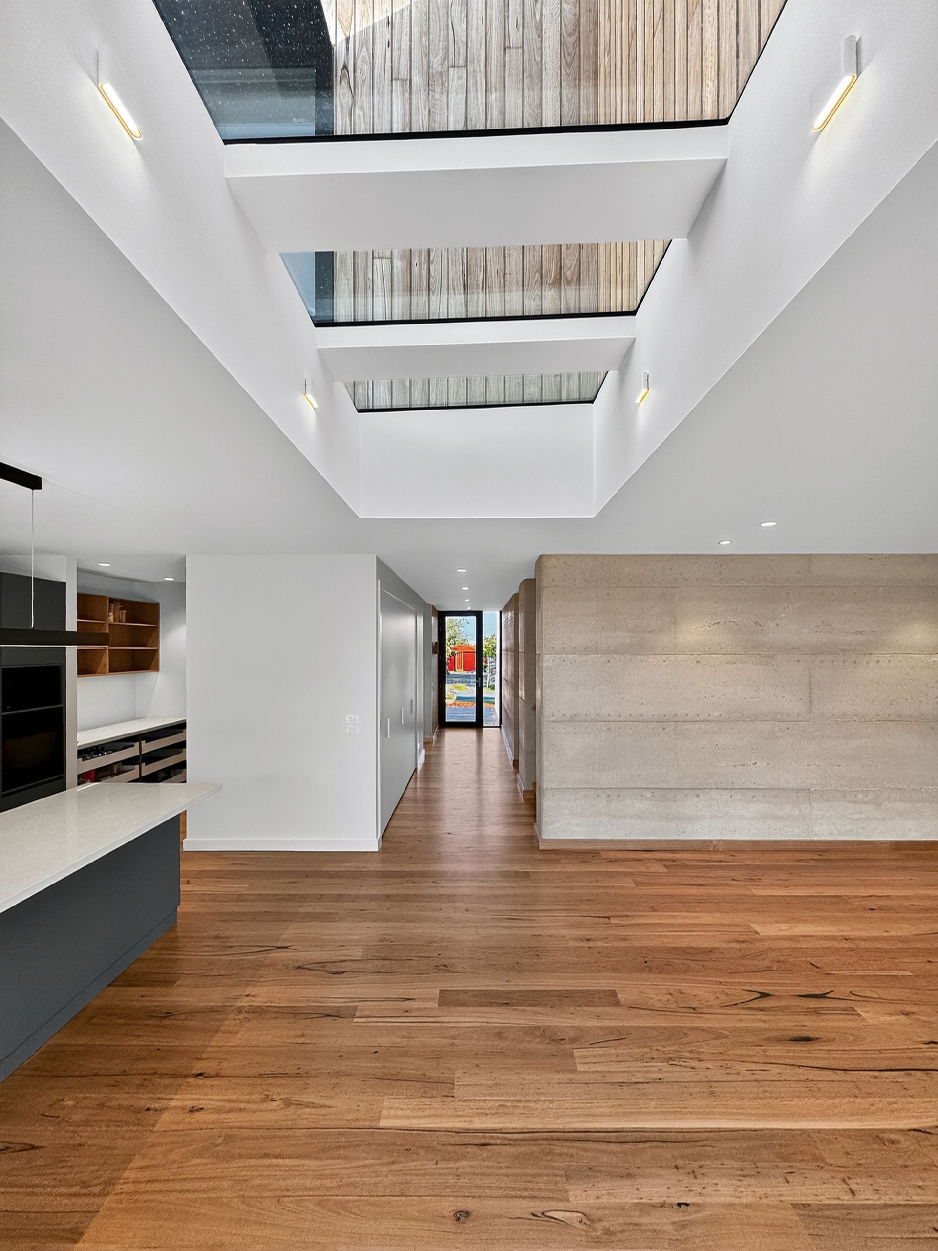 Modern interior with skylights, wood floors, and a concrete wall.