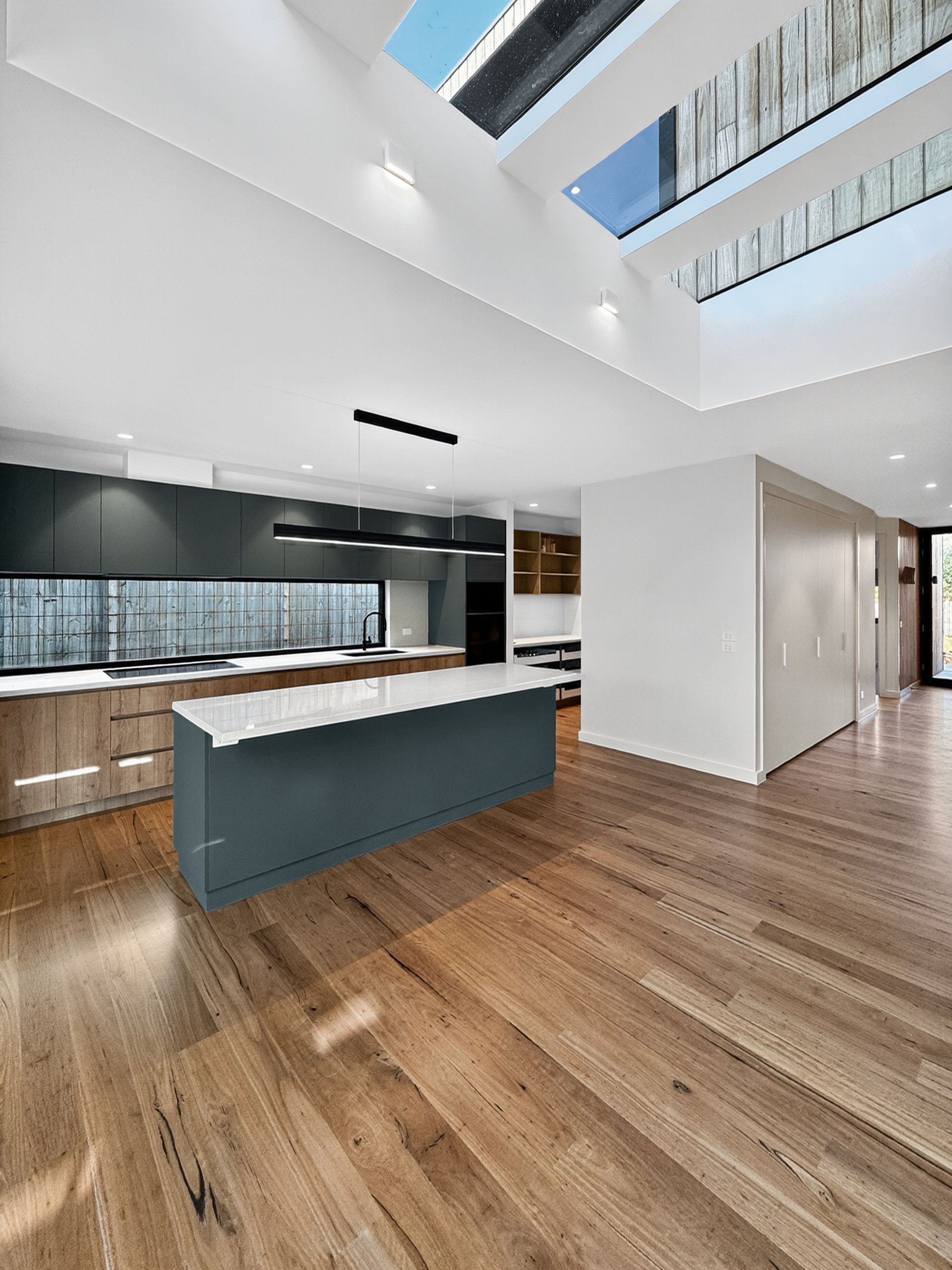 Modern kitchen with wood floors, island, cabinets, and a skylight.