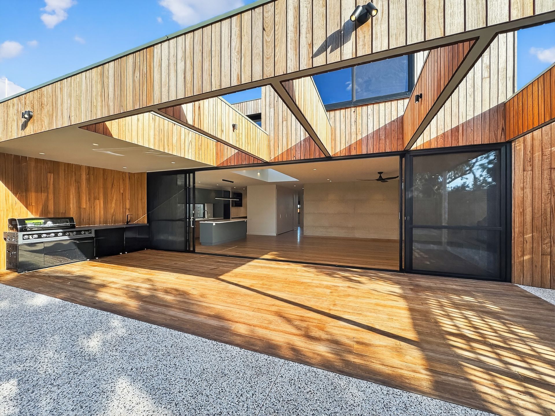 Wooden home exterior with open sliding doors, outdoor deck, and a view of the interior.