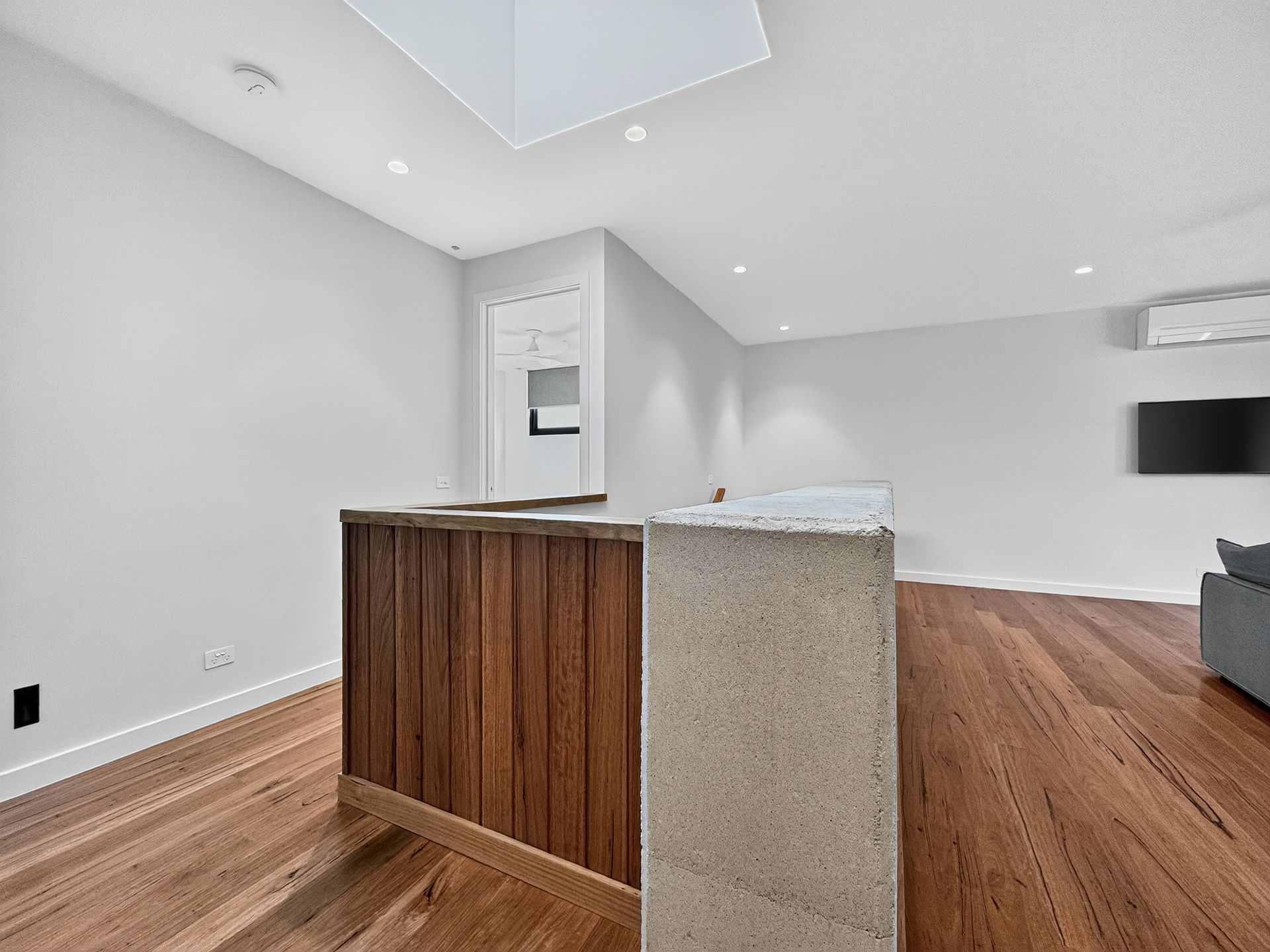 Modern interior with wood flooring, light gray walls, and a wood and concrete counter.