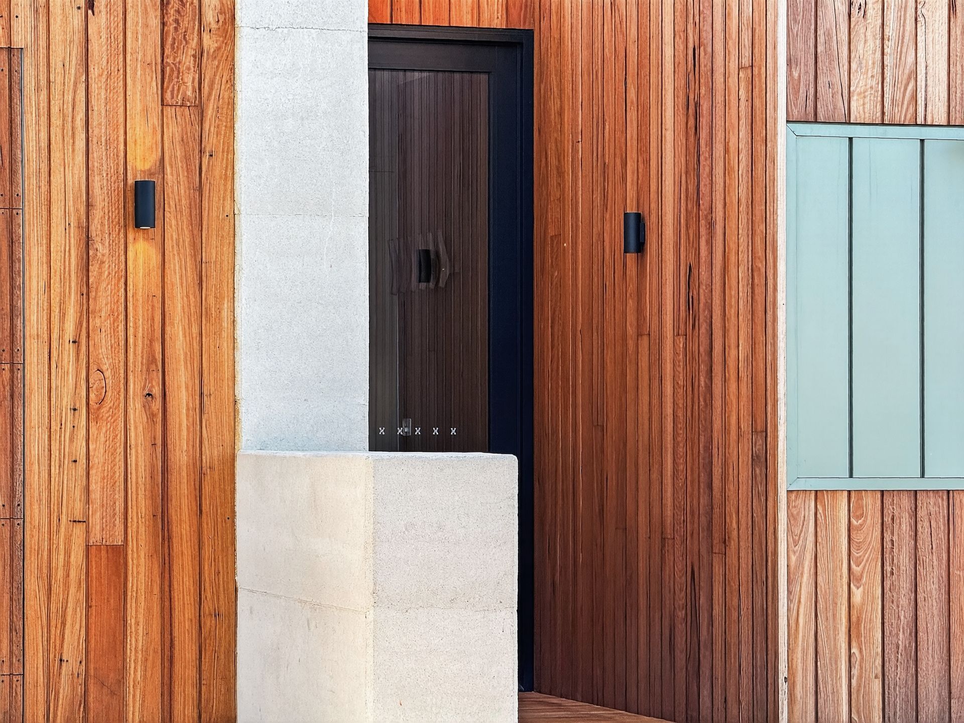 Wooden siding and entryway with dark door and light blue window.