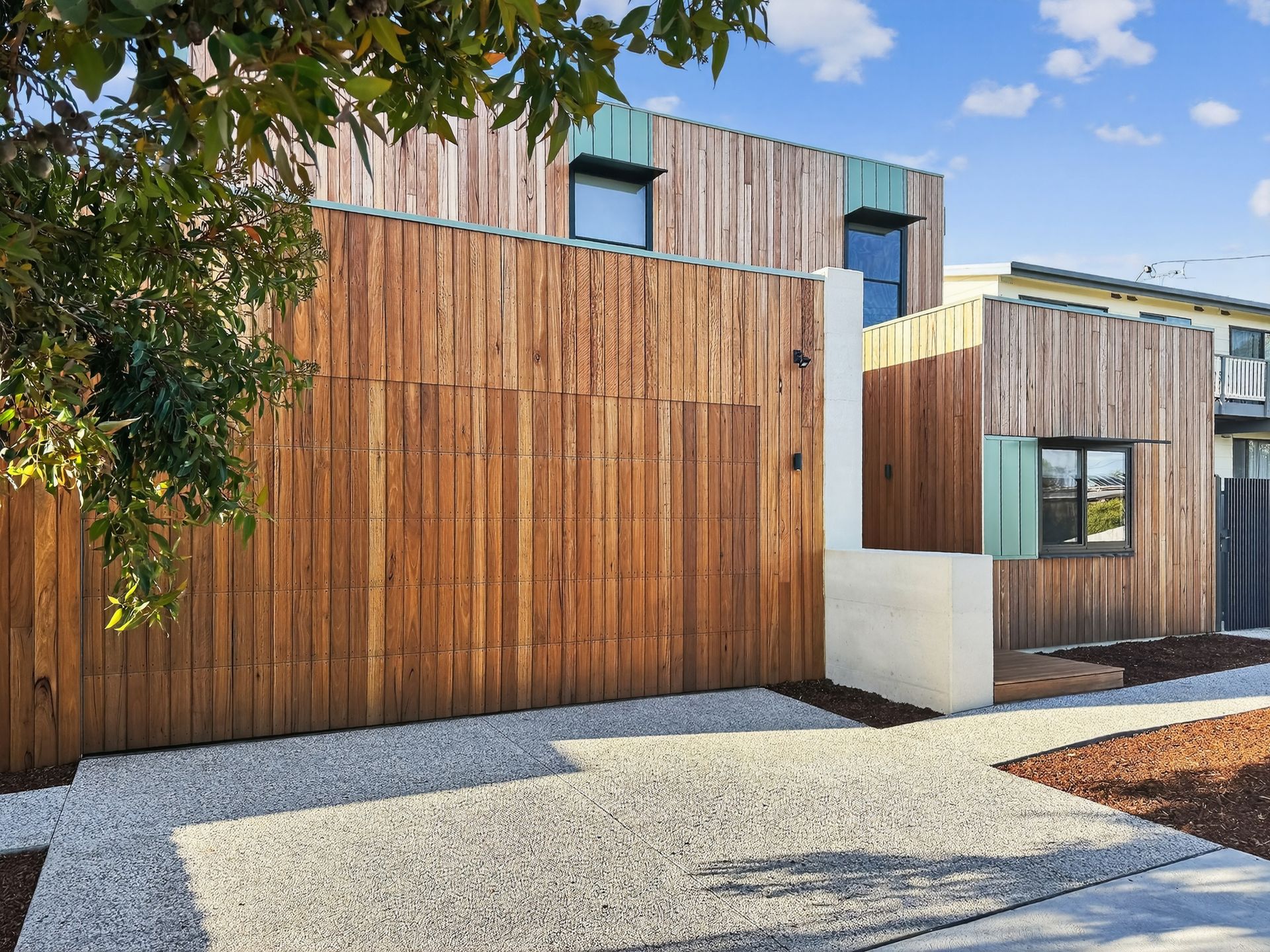 Wooden-clad modern home with gravel path. Exterior with vertical wooden slats and small square windows.