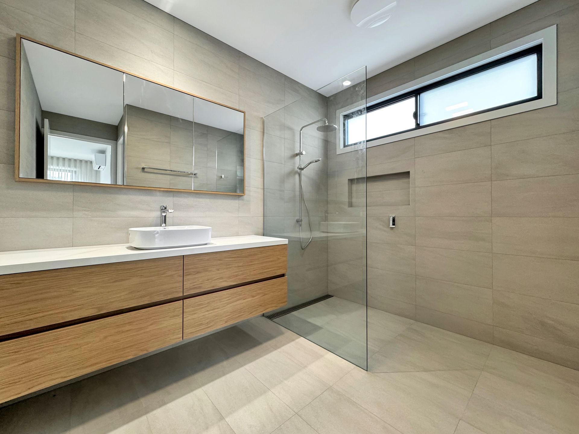 A bathroom with a sink , mirror and walk in shower.