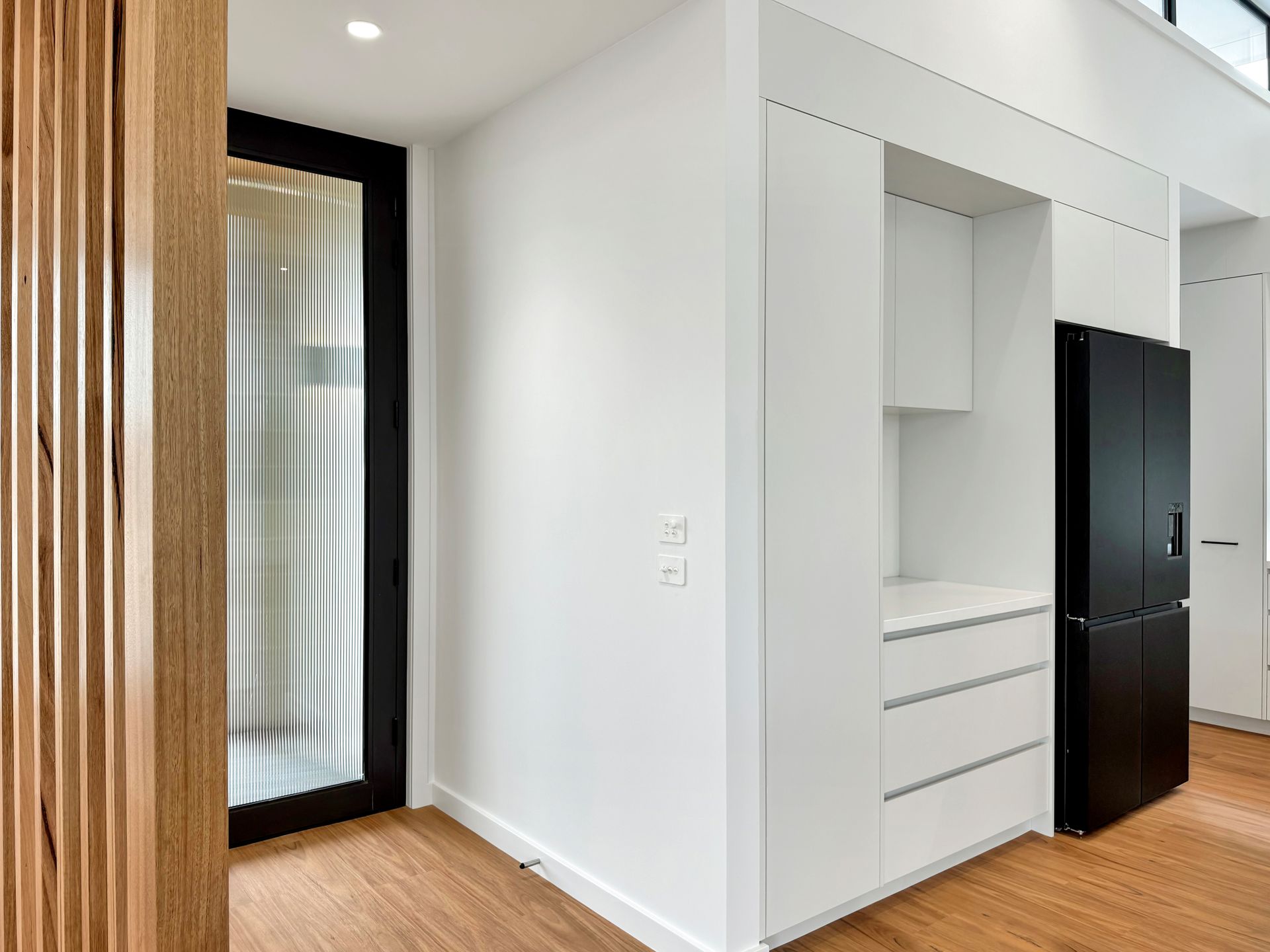 A kitchen with white cabinets and a black refrigerator.