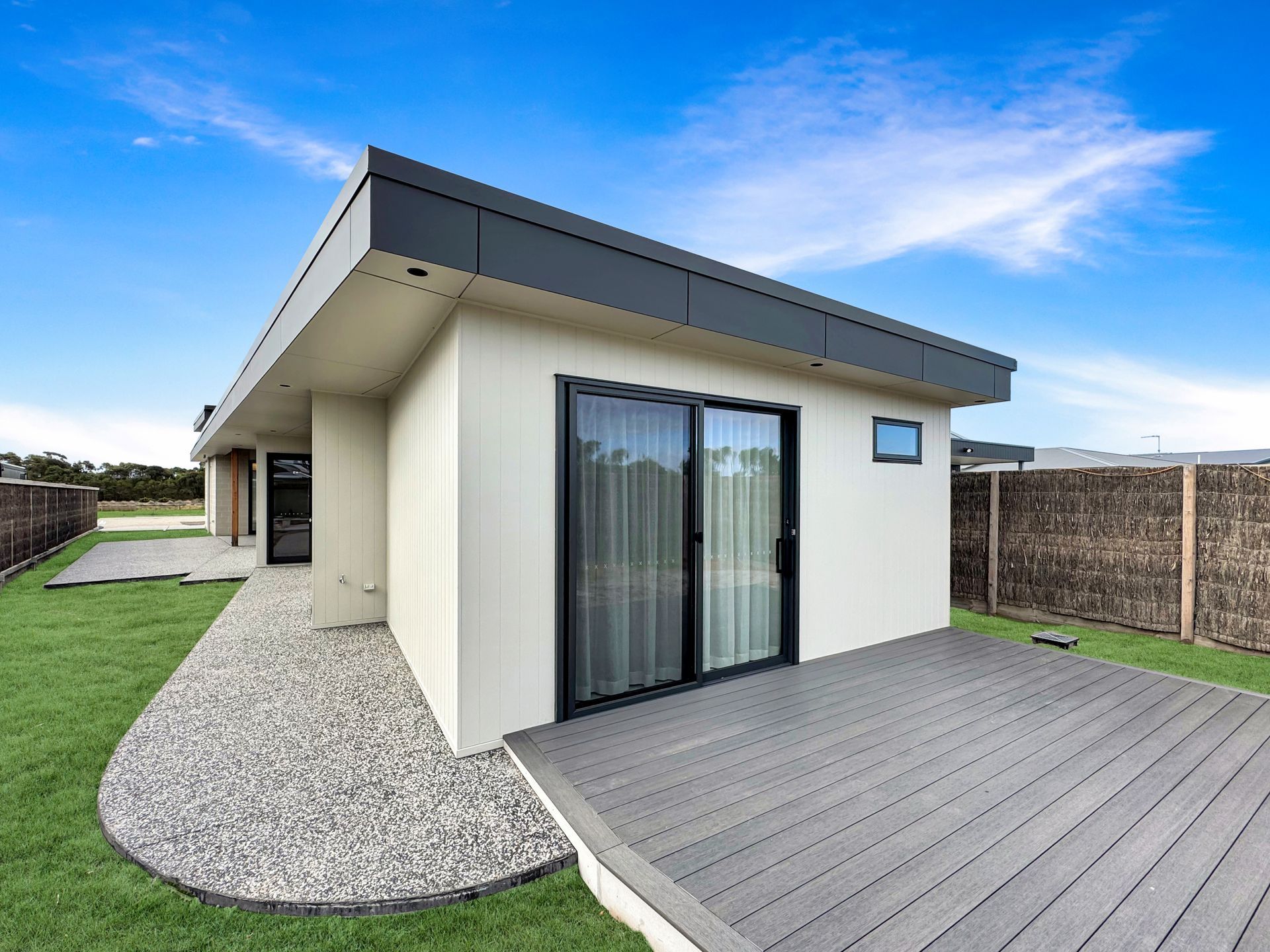 A small house with a deck and sliding glass doors.