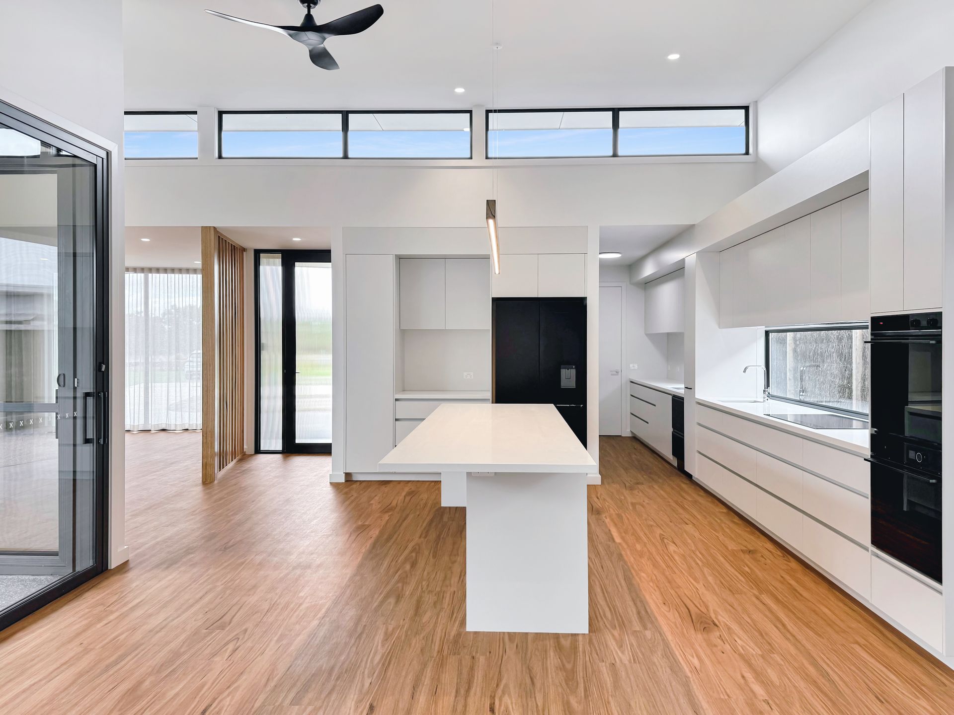 A kitchen with a large island in the middle and a ceiling fan.