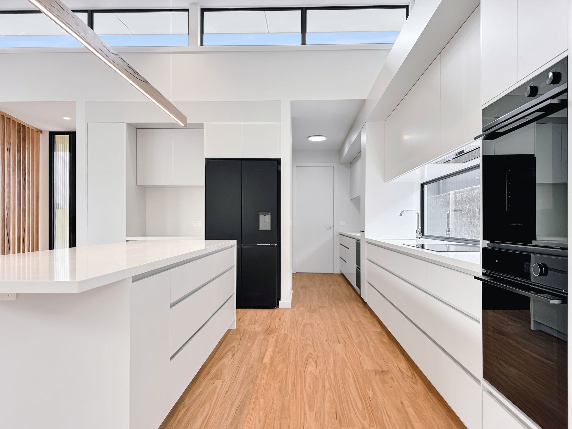 A kitchen with white cabinets , black appliances , and wooden floors.