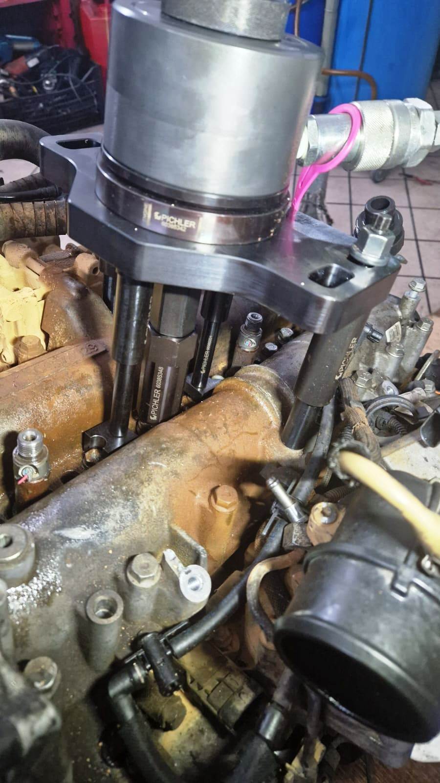 Un meccanico utilizza uno strumento per lavorare su un motore, eventualmente rimuovendone un componente.