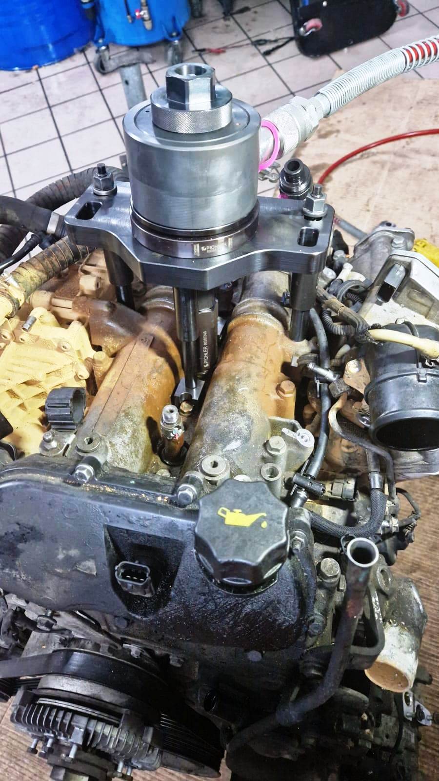 Motore con un attrezzo attaccato, probabilmente per riparazione o manutenzione, in un'officina.