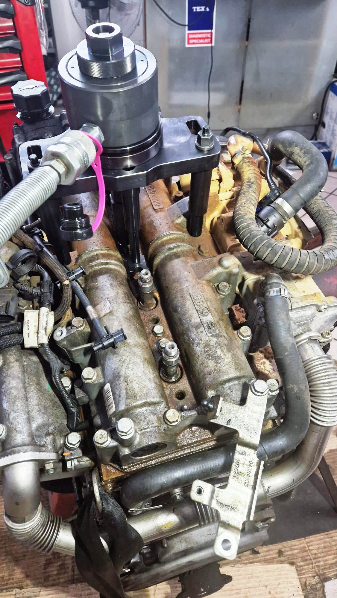 Motore diesel con un componente nero attaccato, vari tubi flessibili e componenti visibili, all'interno.