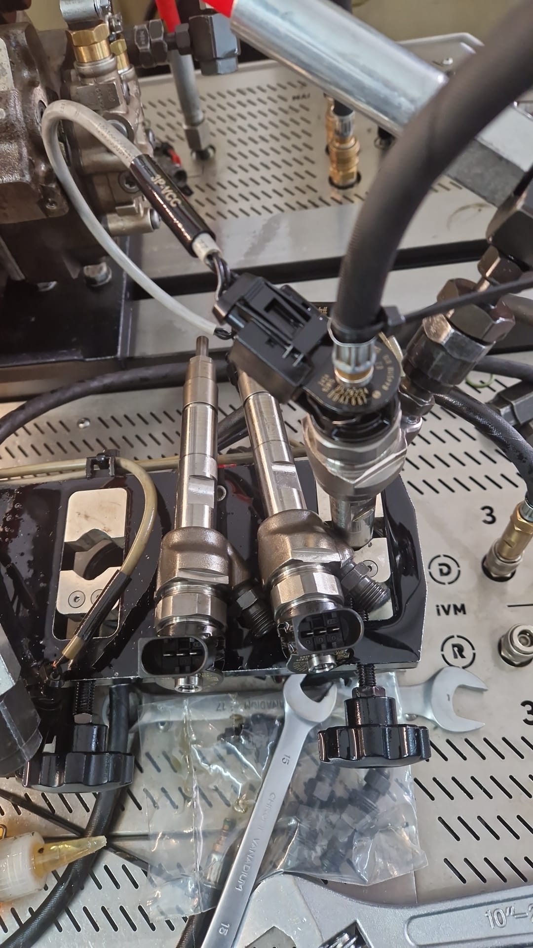 Si lavora sugli iniettori del carburante utilizzando una chiave inglese e connettori elettrici collegati.