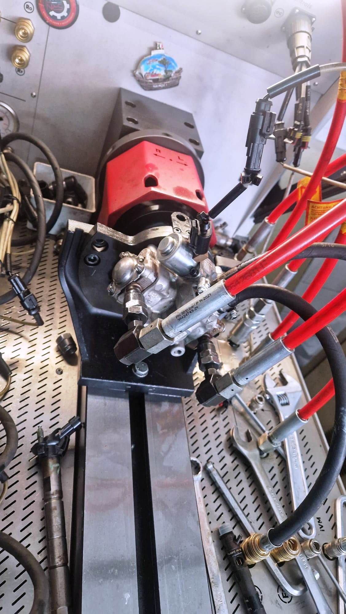 Primo piano di un sistema idraulico, con componenti rossi e neri, montato su un pannello forato con gli attrezzi.