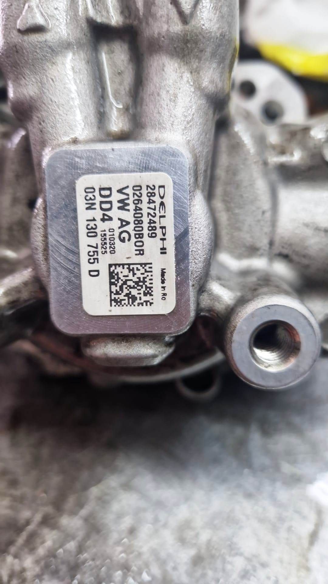 Primo piano di un componente metallico di un'auto con un'etichetta. L'etichetta mostra vari numeri, un codice a barre e la scritta