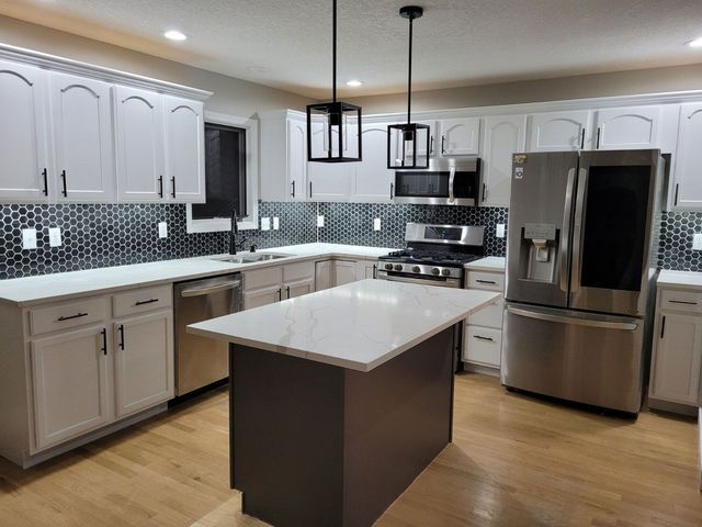 A kitchen with white cabinets and stainless steel appliances.