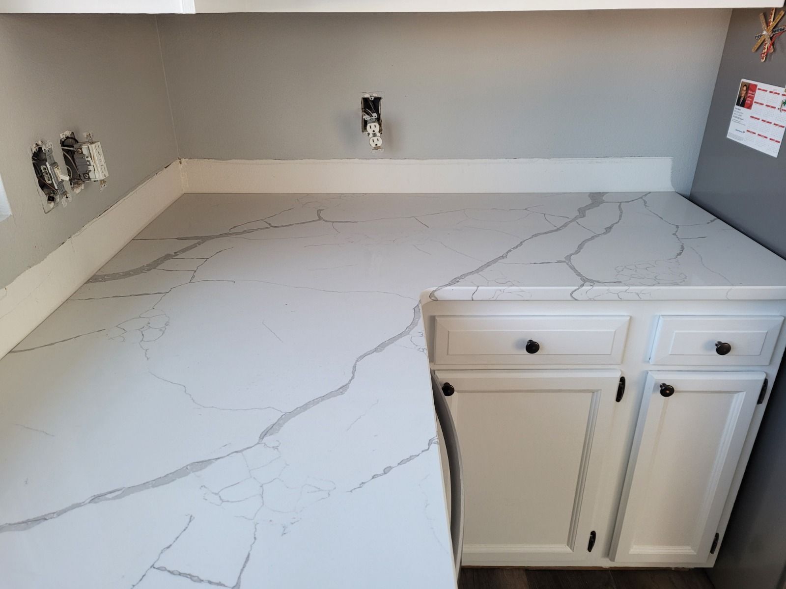 A kitchen with a quartz counter top and white cabinets.