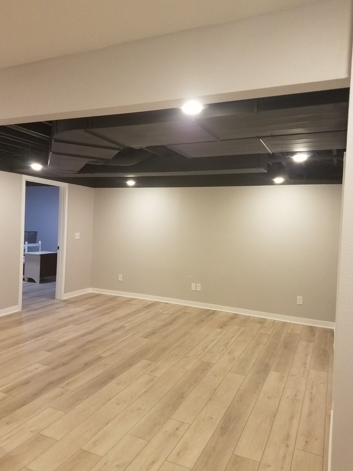 A large empty room with wooden floors and a black ceiling.