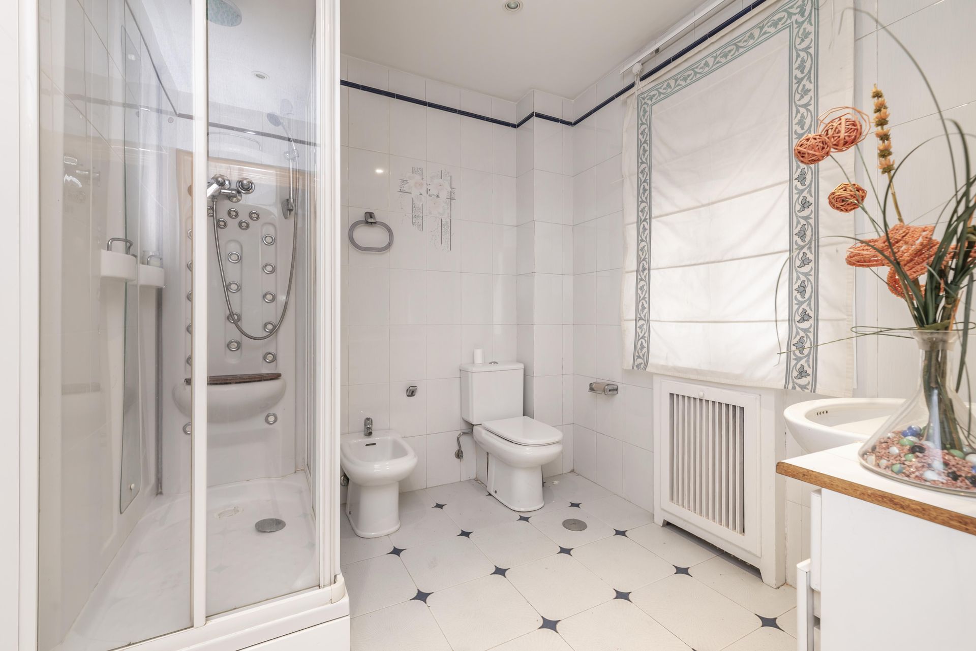 A bathroom with a toilet , bidet , sink and shower.