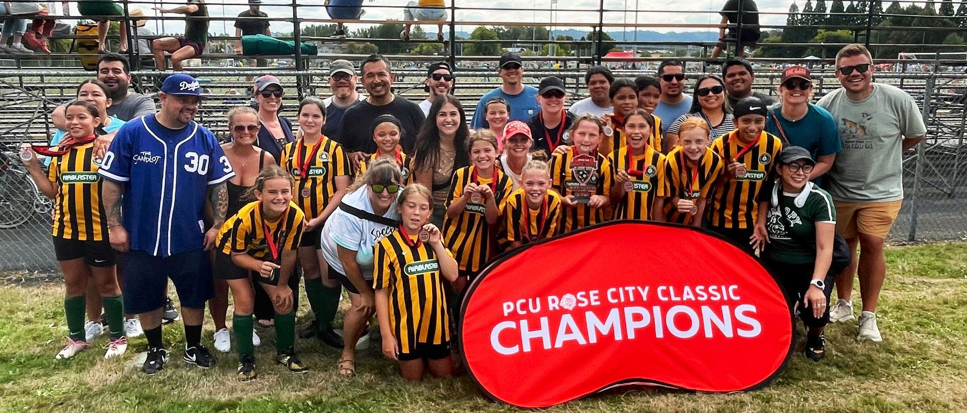 A group of people wearing matching jerseys pose for a photo with a “Champions” sign.