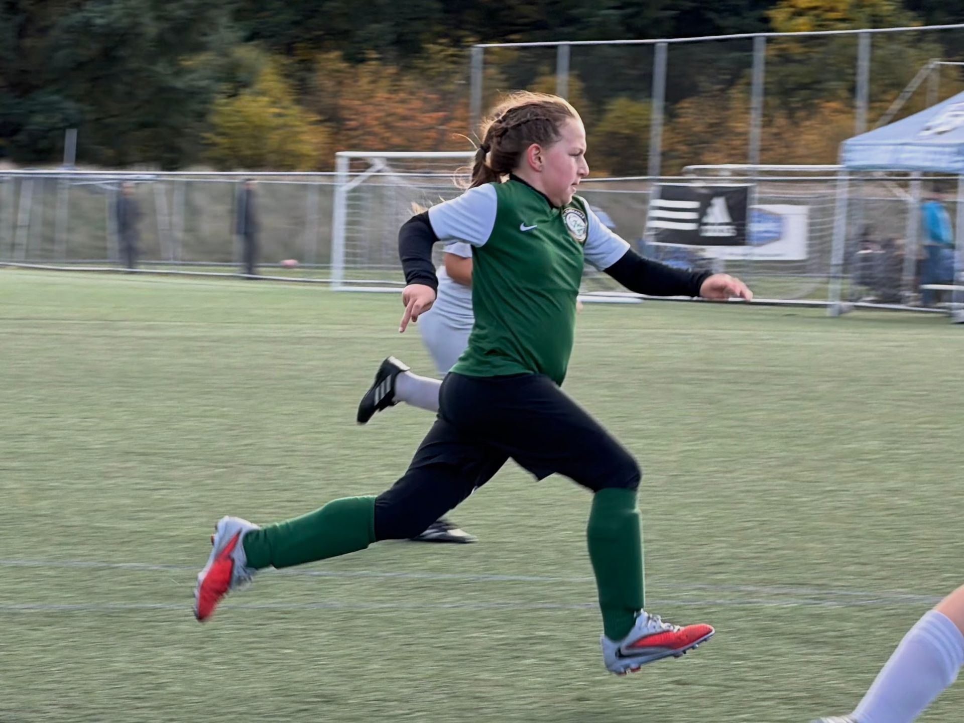 Soccer player in green jersey running on a field during a game.