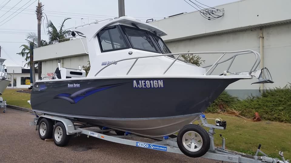 A Grey And White Boat On A Trailer, Parked Outside, With The Registration "AJF818N" — In Tune Marine in Mackay, QLD
