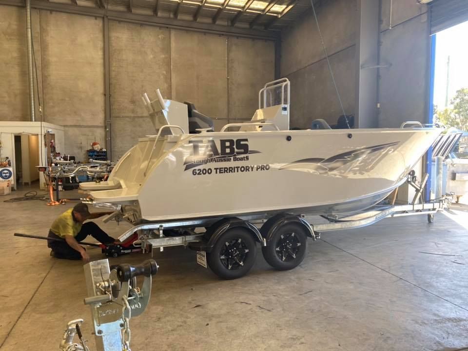 Man Works on a Boat Trailer Inside a Gray-walled Workshop — In Tune Marine in West End, QLD