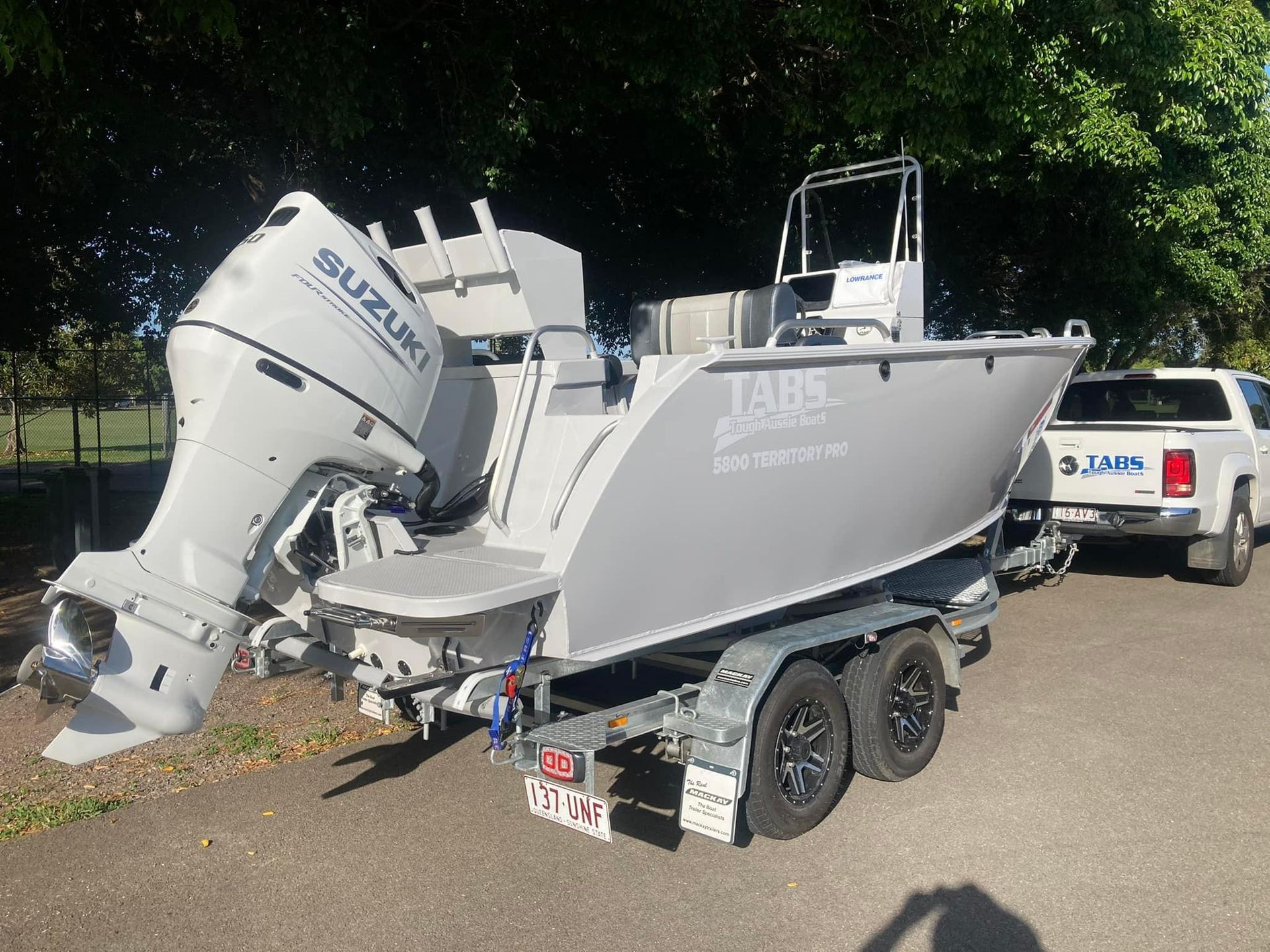 Gray Boat On A Trailer With A Suzuki Outboard Motor. A White Truck Is Parked Nearby — In Tune Marine in Mackay, QLD