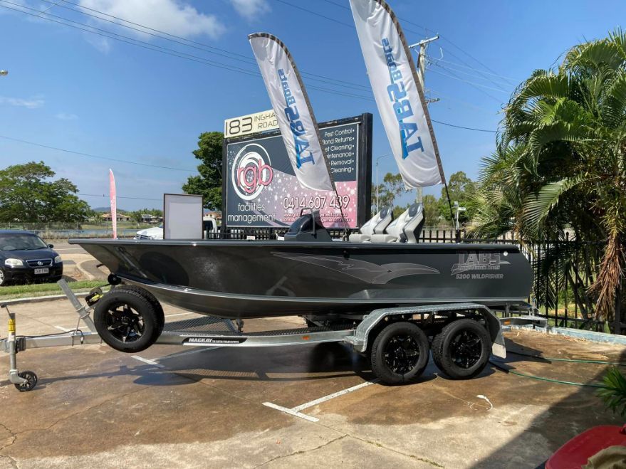 Gray Boat on Trailer at a Boat Dealership With Flags and a Sign on a Sunny Day — In Tune Marine in Cairns, QLD